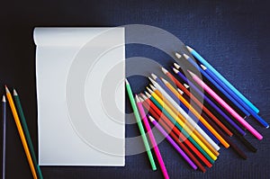 Top view pencils and blank white paper notebook mock up with colorful chalk pencil on white isolated background