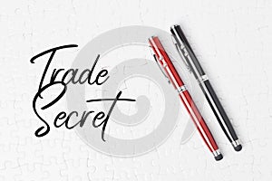 Top view of pens on a jigsaw puzzle texture with a writing of "Trade secret"-  Business concept