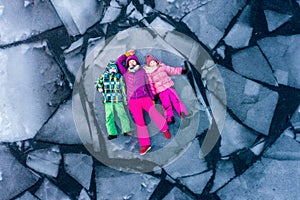 Top view of people lying on ice alone. Woman and children in bright clothes on broken ice block in water. Winter cracked photo