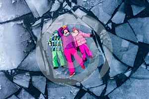 Top view of people lying on ice alone. Woman and children in bright clothes on broken ice block in water. Winter cracked