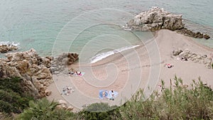 Top view of people relaxing and tanning on beach near sea in cloudy afternoon.