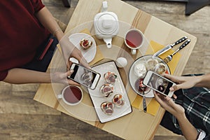 top view of people using smartphones and photographing appetizers