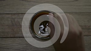 Top view of person hand stirring hot coffee in a cup with spoon.