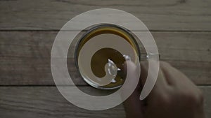 Top view of person hand stirring hot coffee in a cup with spoon.