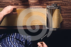 Top view of a person rolling the dough using a dough roller sheeter