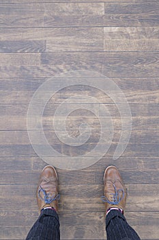 Top view of a person wearing brown Brogue shoes and standing on a wooden floor