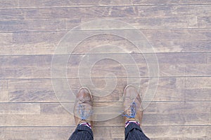 Top view of a person wearing brown Brogue shoes and standing on a wooden floor