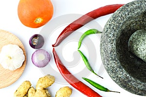 Top view of pestle and mortar with cooking ingredients over white background