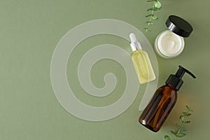 Top view photo of amber pump bottle, dropper bottle, cream jar and eucalyptus leaves