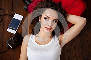 Top view photo of beautiful girl lying on wooden floor. Young woman with thoughts on cloud. Passport, tickets, vintage