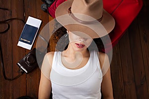 Top view photo of beautiful girl lying on wooden floor. Young woman with thoughts on cloud. Passport, tickets, vintage