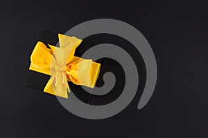 Top view photo of black gift box with ribbon wrapped as a bow isolated on black background