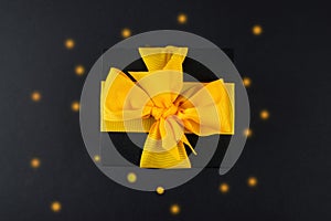 Top view photo of a black gift box with a yellow bow