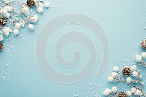 Top view photo of christmas decorations snow branches with pine cones on isolated pastel blue background with copyspace