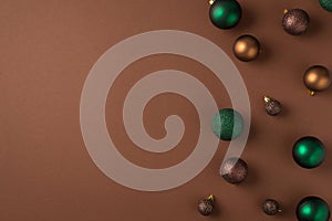 Top view photo of christmas tree decorations green brown and golden balls on isolated brown background with copyspace