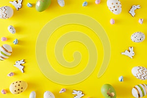 Top view photo of color eggs and cute easter bunnies on yellow background