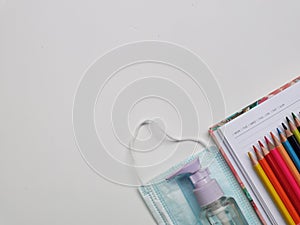 Top view photo of colorful pencil,note book,medical face mask and hand sanitizer isolated on white background.