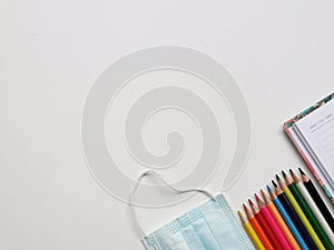 Top view photo of colorful pencil,note book,medical face mask and hand sanitizer isolated on white background.