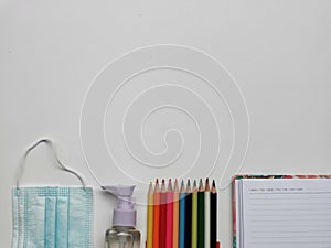 Top view photo of colorful pencil,note book,medical face mask and hand sanitizer isolated on white background.