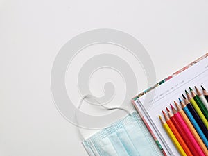 Top view photo of colorful pencil,note book,medical face mask and hand sanitizer isolated on white background.