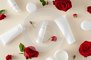 Top view photo of cosmetic tubes with cream without label, cream jars and red flowers