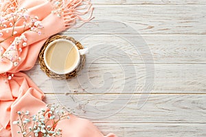 Top view photo of cup of coffee on rattan serving mat gypsophila flowers and pink plaid on grey wooden desk background