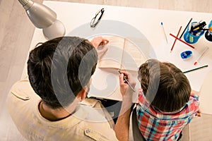 Top view photo of dad helping his son with home task