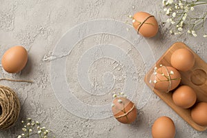 Top view photo of easter decorations brown easter eggs white gypsophila flowers spool of twine and wooden egg holder on isolated