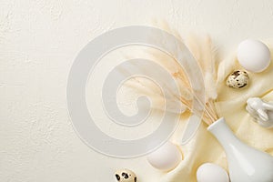 Top view photo of easter decorations white vase with bouquet of lagurus flowers ceramic easter bunny eggs and textile on isolated