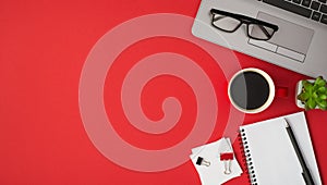 Top view photo of glasses on laptop flowerpot red cup of coffee binder clips white sticker note paper and pen on open spiral