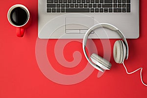 Top view photo of grey laptop red cup of drink and white bright headphones on isolated red background with copyspace