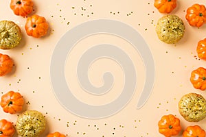 Top view photo of halloween decorations orange golden small pumpkins and golden sequins on isolated beige background with