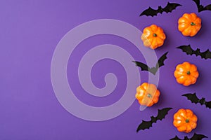 Top view photo of halloween decorations small pumpkins and bats silhouettes on isolated violet background with empty space