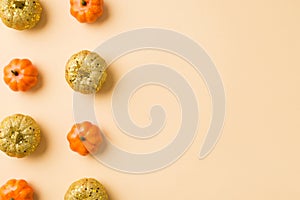 Top view photo of halloween decorations two rows of orange and golden small pumpkins on isolated beige background with copyspace