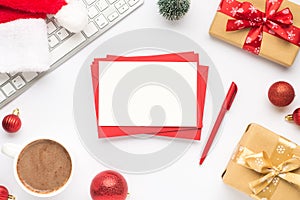 Top view photo of keyboard cup of hot drinking santa claus hat pine toy red christmas tree balls gift boxes stack of red envelopes