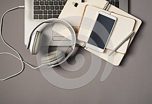 Top view photo of laptop keyboard wired white headset grey pen and mobile phone on two open organizers on isolated grey background