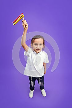 Top view photo of little boy, Jewish kid looking at camera and shows grogger to camera against purple background