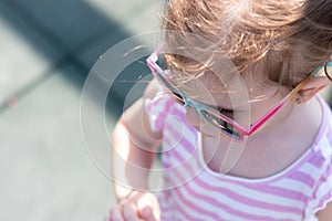Top view photo of a little girl in sunglasses and pigtails closeup