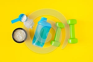 Top view photo made of protein powder in jar with sport shaker bottle and dumbbells on yellow background