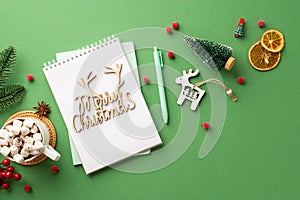 Top view photo of merry christmas wooden text diary pen pine branch mug of cocoa with marshmallow wood deer ornament mistletoe