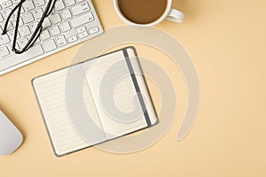 Top view photo of open diary glasses white keyboard mouse and cup on isolated beige background with copyspace