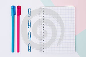 Top view photo of open empty spiral notebook, paper clips and pe