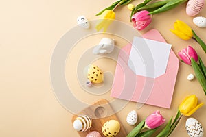 Top view photo of pink envelope with paper sheet colorful easter eggs ceramic easter bunny tulips and wooden egg holder