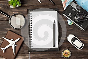 Top view photo of planner and pen in the center plane and car models camera map magnifier compass passport cover and plant on