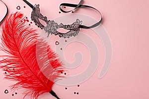 Top-view photo of sensual tools lace mask, feather tickler, confetti on pastel pink background, space for text