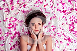 Top view photo of shiny cute woman dressed sexy singlet hands cheeks lying pink flowers isolated white sheet background