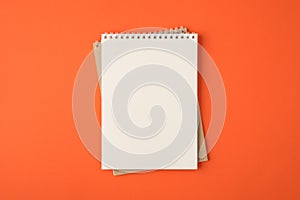 Top view photo of spiral notebooks on isolated vivid orange background with blank space