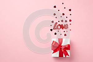 Top view photo of st valentine`s day decorations white giftbox with red ribbon bow inscription love and red heart shaped confetti