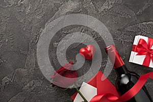 Top view photo of valentine`s day decor wine bottle white giftbox with red bow silk ribbon heart envelope with card and red rose