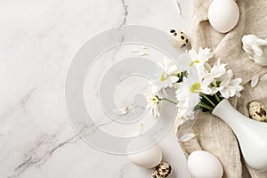 Top view photo of the vase with daisies eggs on the textured cloth and ceramic rabbit on isolated marble background copyspace